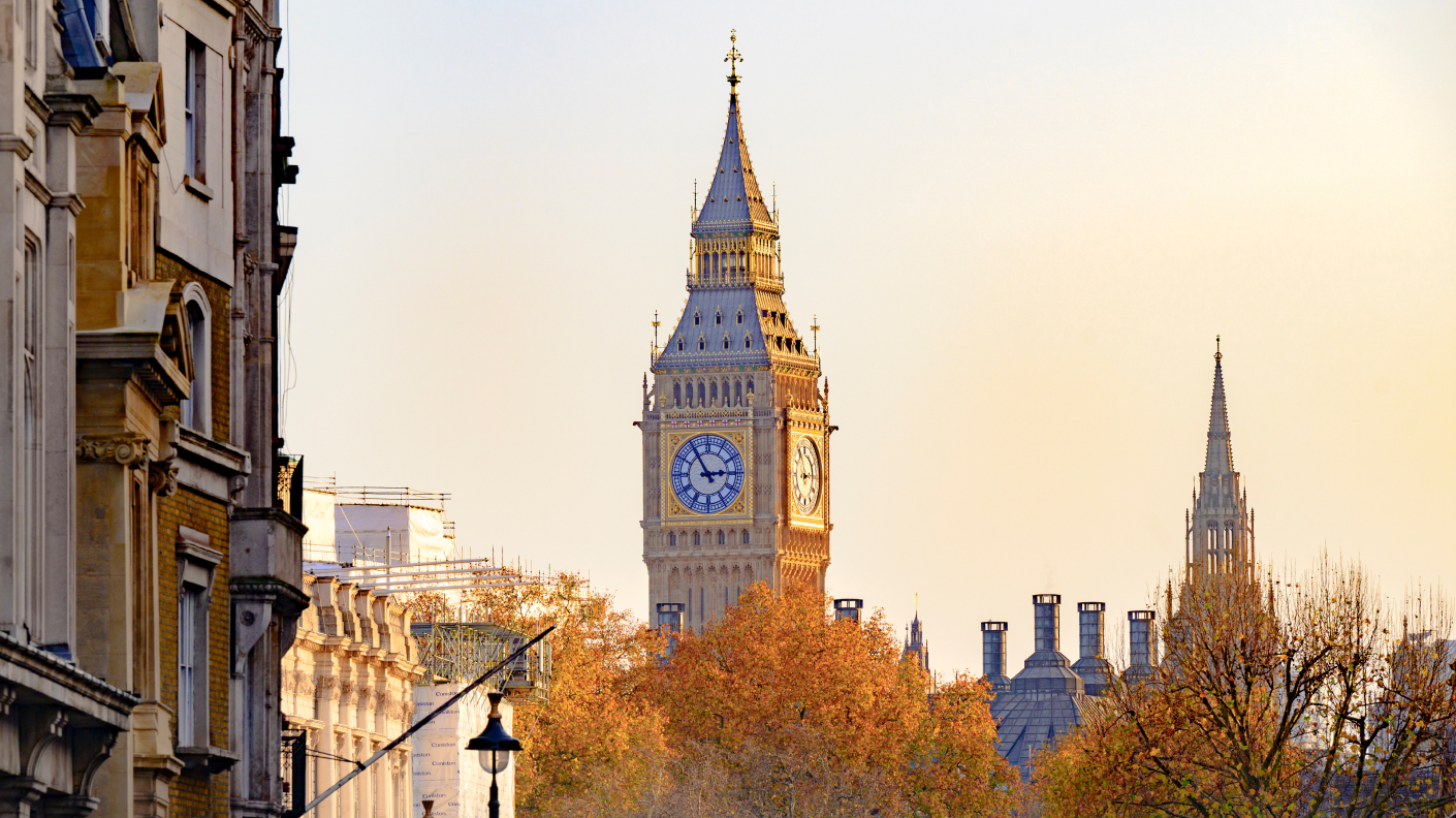 A picture of London rooftops with the Big Ben clock and golden autumn trees